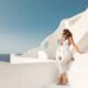 woman standing in a white dress in Greece with the blue sky in the background