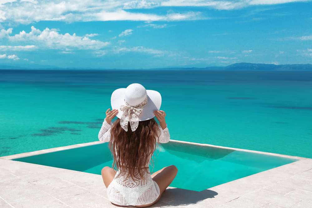 When thinking about what to wear in the Maldives channel this model: as she overlooks the water, she wears a white cover up, a white bikini, and a white sun hat.  