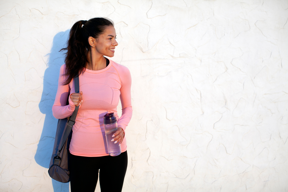 When wondering what to wear on a cruise think of clothes for excursions too: this woman has a moisture wicking pink top, black leggings, and a reusable water bottle with her! 