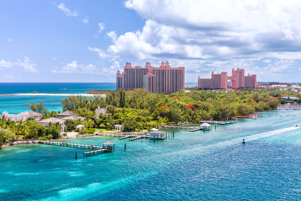 ocean and a waterway with a piece of land between them, there's tall buildings and smaller homes on the land, it is a bright but cloudy day 