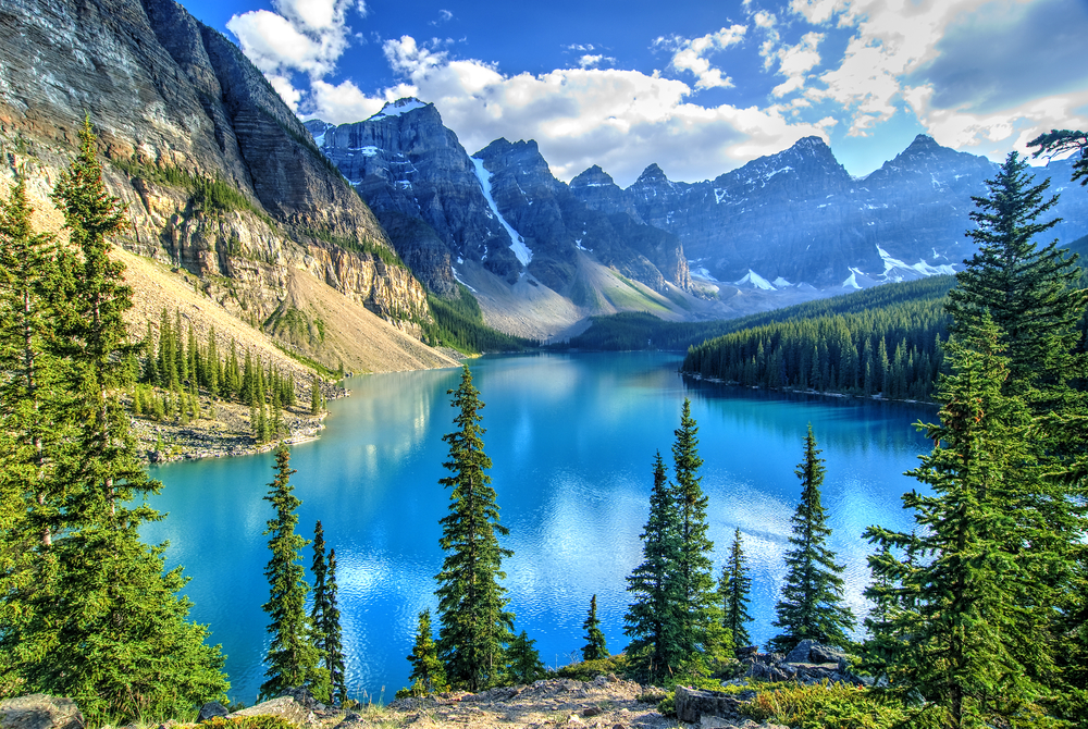 a mountainscape with a large lake in the middle of it, there are clouds in the sky, one of the top 40th birthday trip ideas