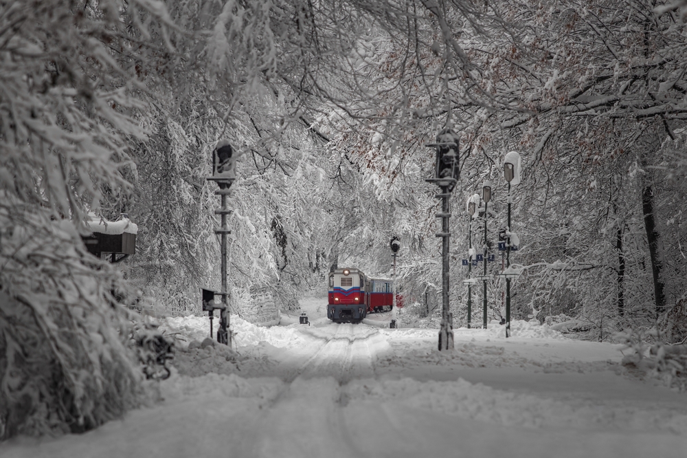 a train coming through the snow into the city of Budapest 