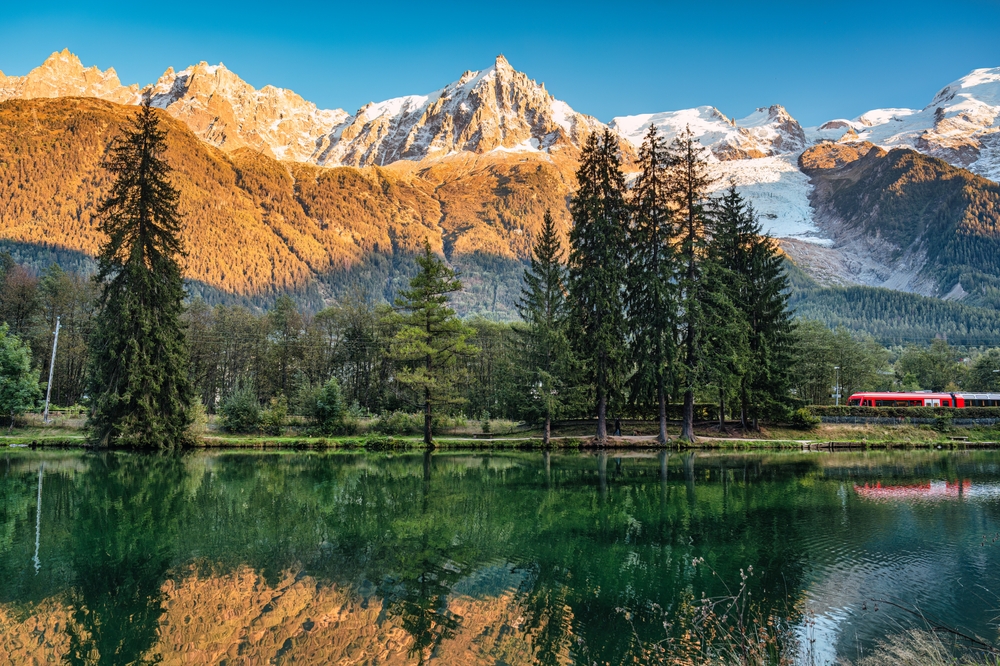 a beautiful Europe by train journey through France with a lake, snow covered mountains and trees