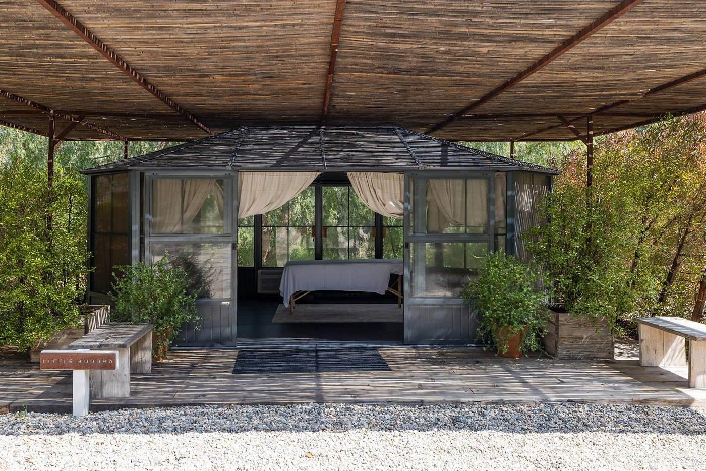 One of the luxurious treatment rooms with thatched roof, massage table and outdoor zen garden at the Ranch Malibu