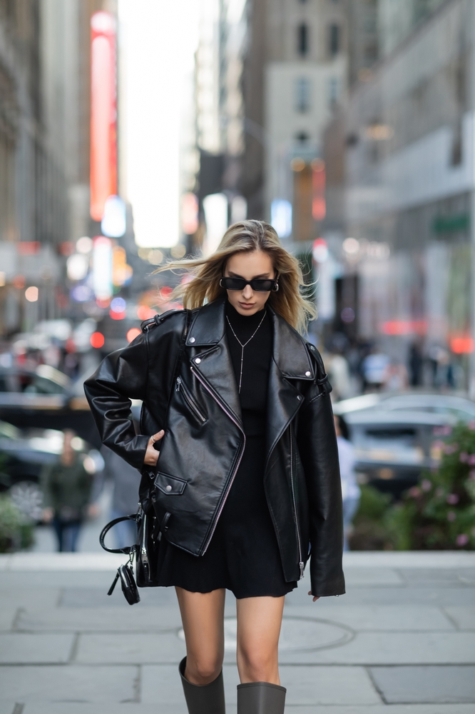 When wondering what to wear in New York City in winter, you don't have to sacrifice style for comfort: thick knit sweater dresses like this woman is wearing and leather jackets will keep you warm and stylish. 